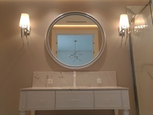 Большое круглое зеркало в серебряной раме в интерьере ванной