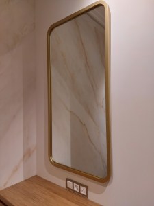 Прямоугольное зеркало в золотой раме с закругленными углами в интерьере спальни