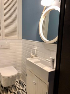 Круглое зеркало в раме белого цвета на кожаном ремне в ванной