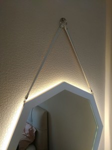Белое зеркало октагон на ремне с подсветкой в интерьере спальни