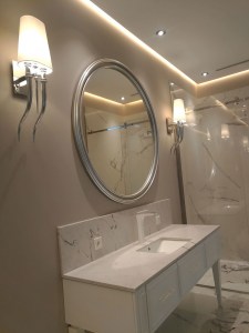 Большое круглое зеркало в серебряной раме в интерьере ванной