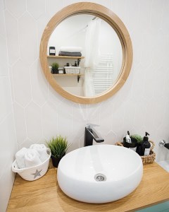 Круглое зеркало в раме из дуба в интерьере ванной в скандинавском стиле